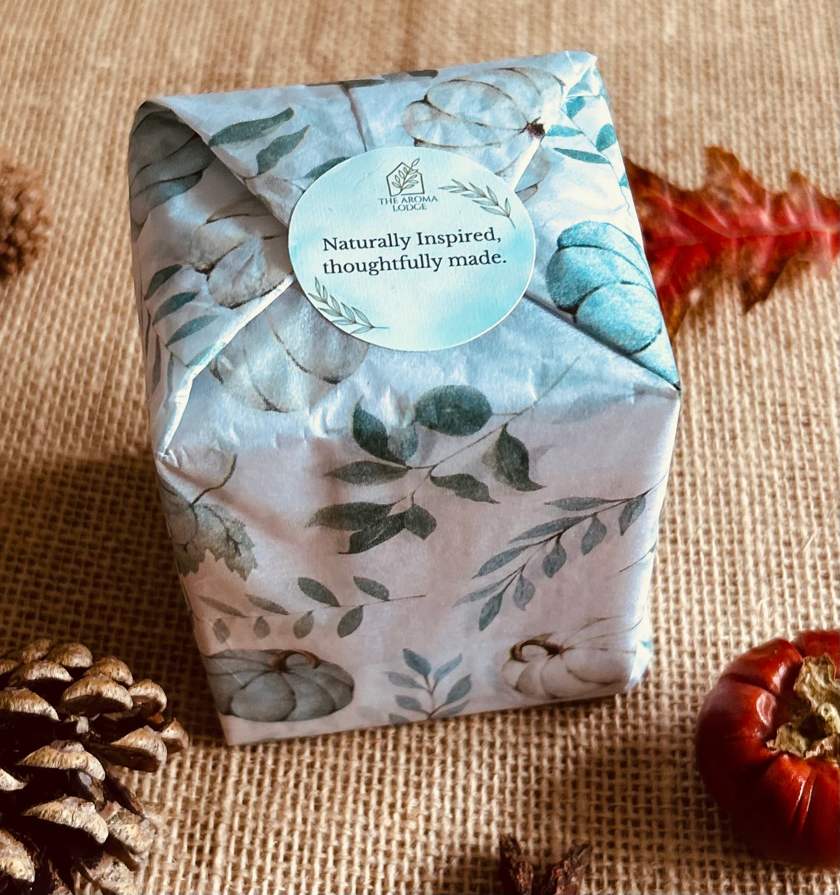Gift box wrapped in nature-themed paper with a visible brand tag on a textured surface.