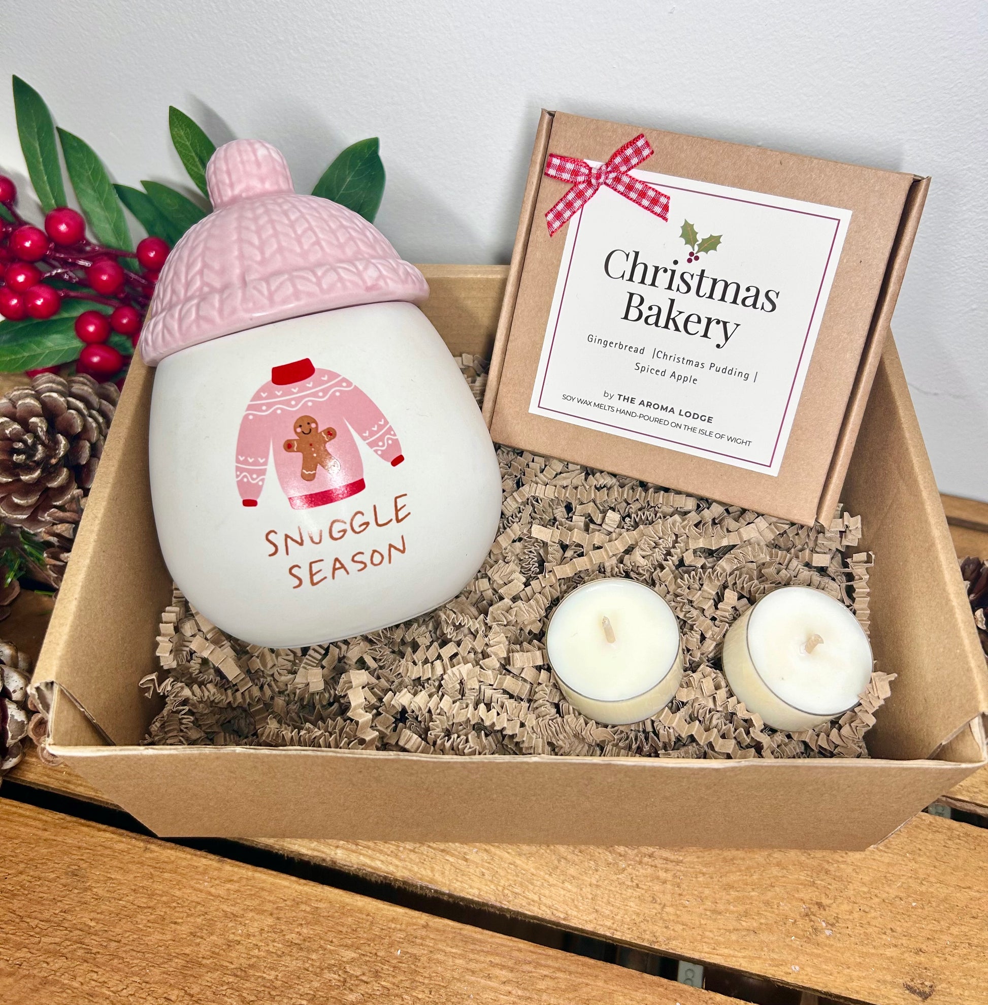Candle with pink knit cap and 'Snuggle Season' text in a gift box with Christmas Bakery packaging.