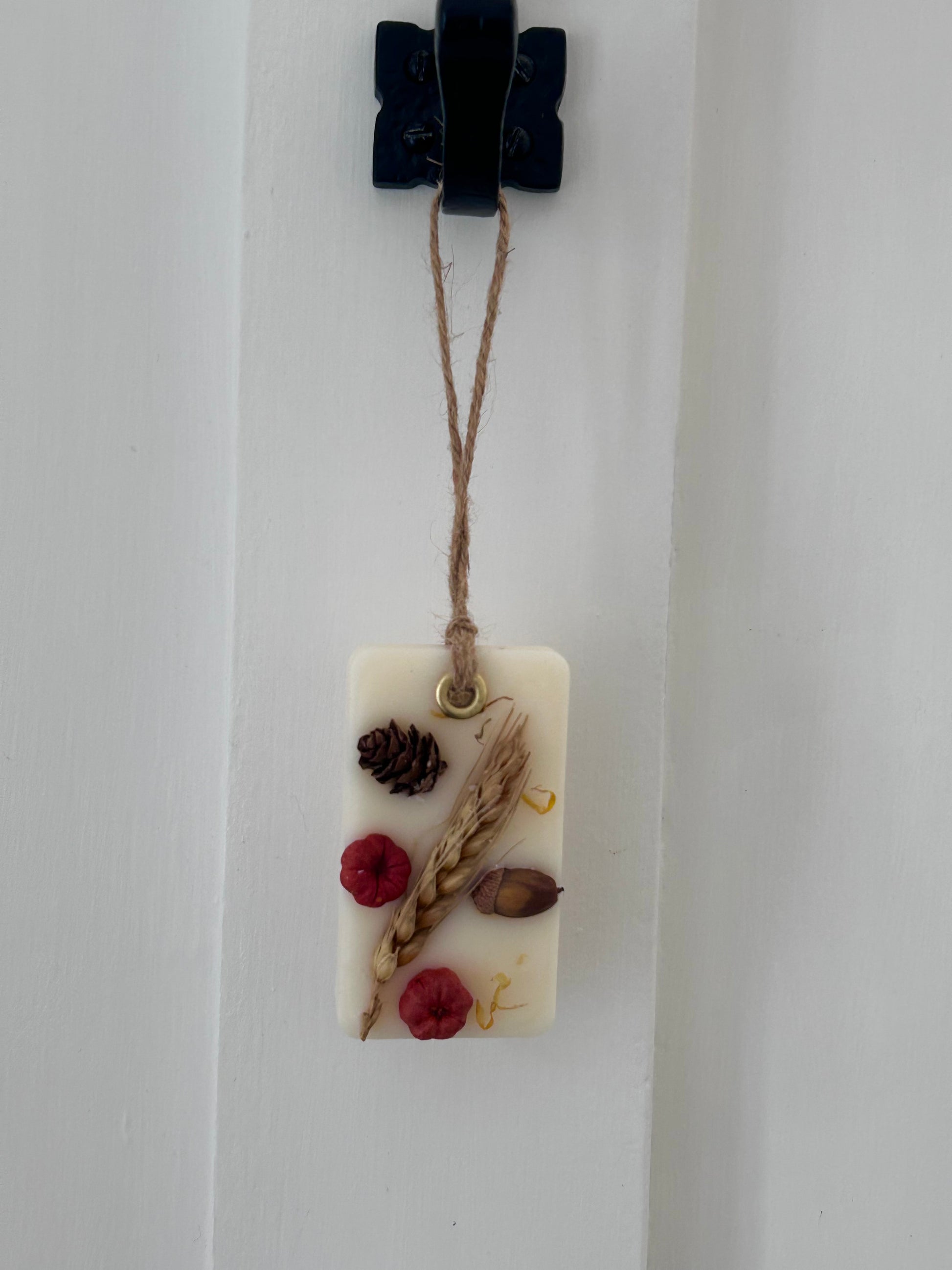 Decorative wax melt handing sachet with natural elements on a white background