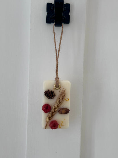 Decorative wax melt handing sachet with natural elements on a white background