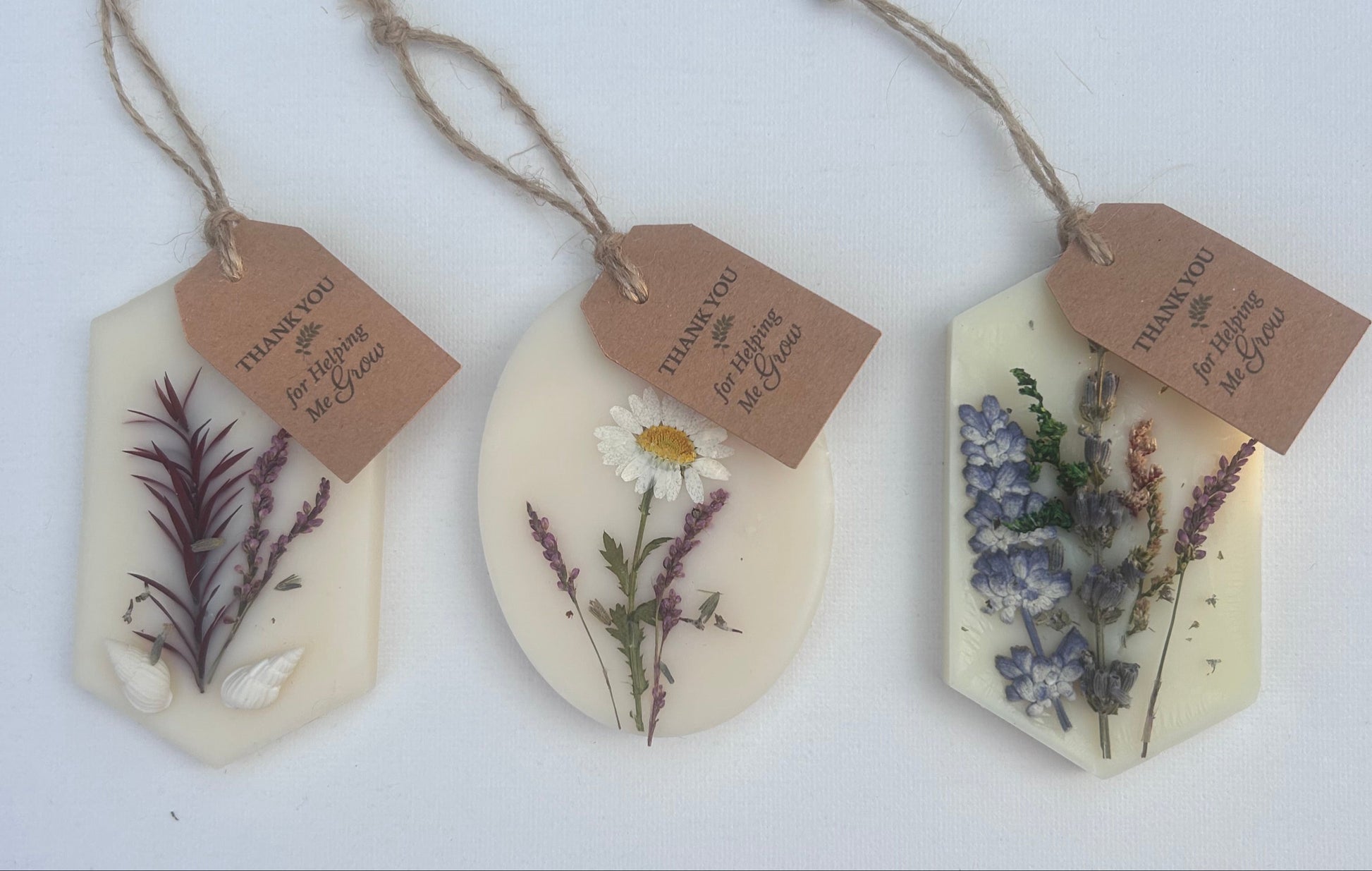 Decorative wax melts sachets with floral elements and tags on a white surface