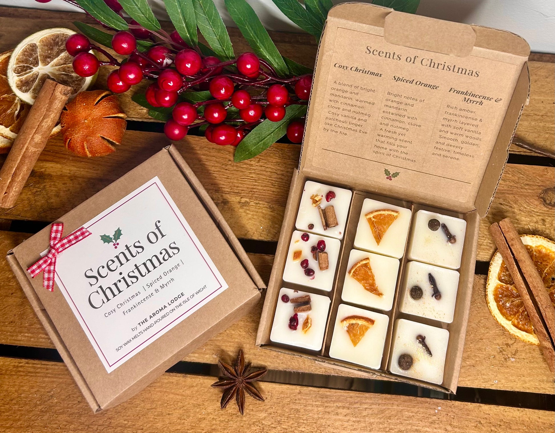 Box of 'Scents of Christmas' candles with decorative elements on a wooden surface.